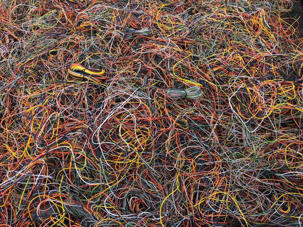 A pile of tangled wires of different colors.